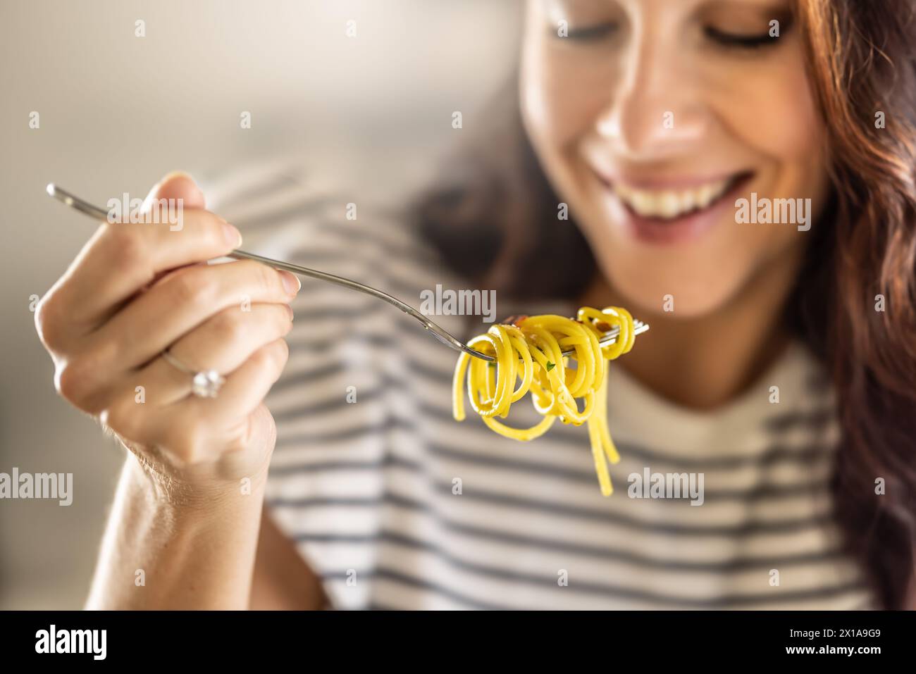 Die junge Frau isst gern Spaghetti. Er hat Aglio e Olio Pasta auf seiner Gabel verdreht. Stockfoto