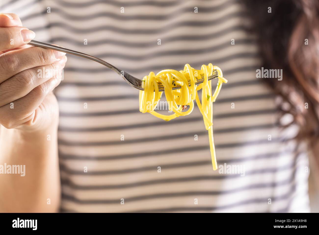 Die junge Frau isst gern Spaghetti. Er hat Aglio e Olio Pasta auf seiner Gabel verdreht. Nahaufnahme. Stockfoto