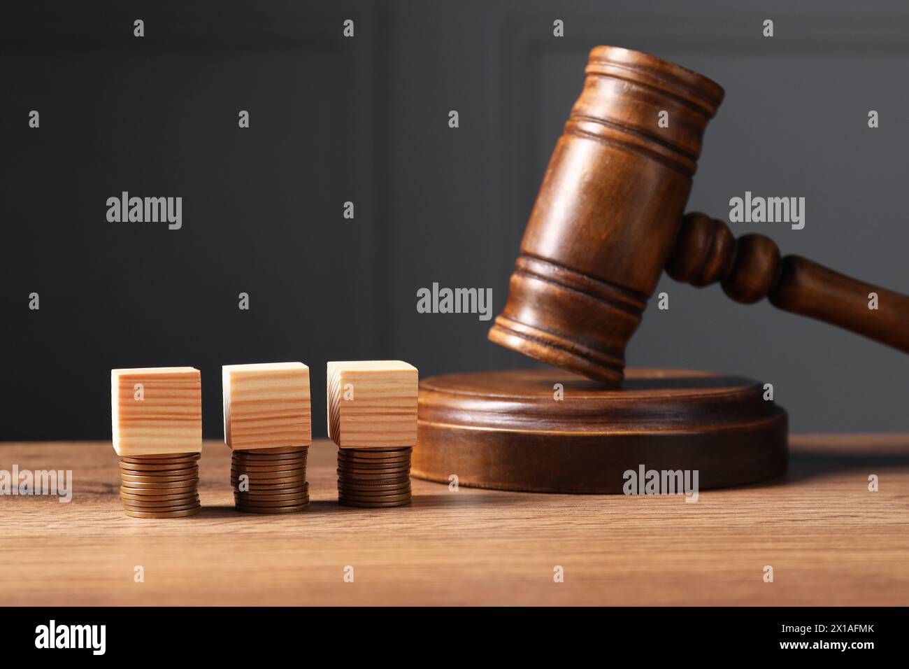 Steuerrecht. Leere Holzwürfel, gestapelte Münzen und Hammer auf dem Tisch Stockfoto