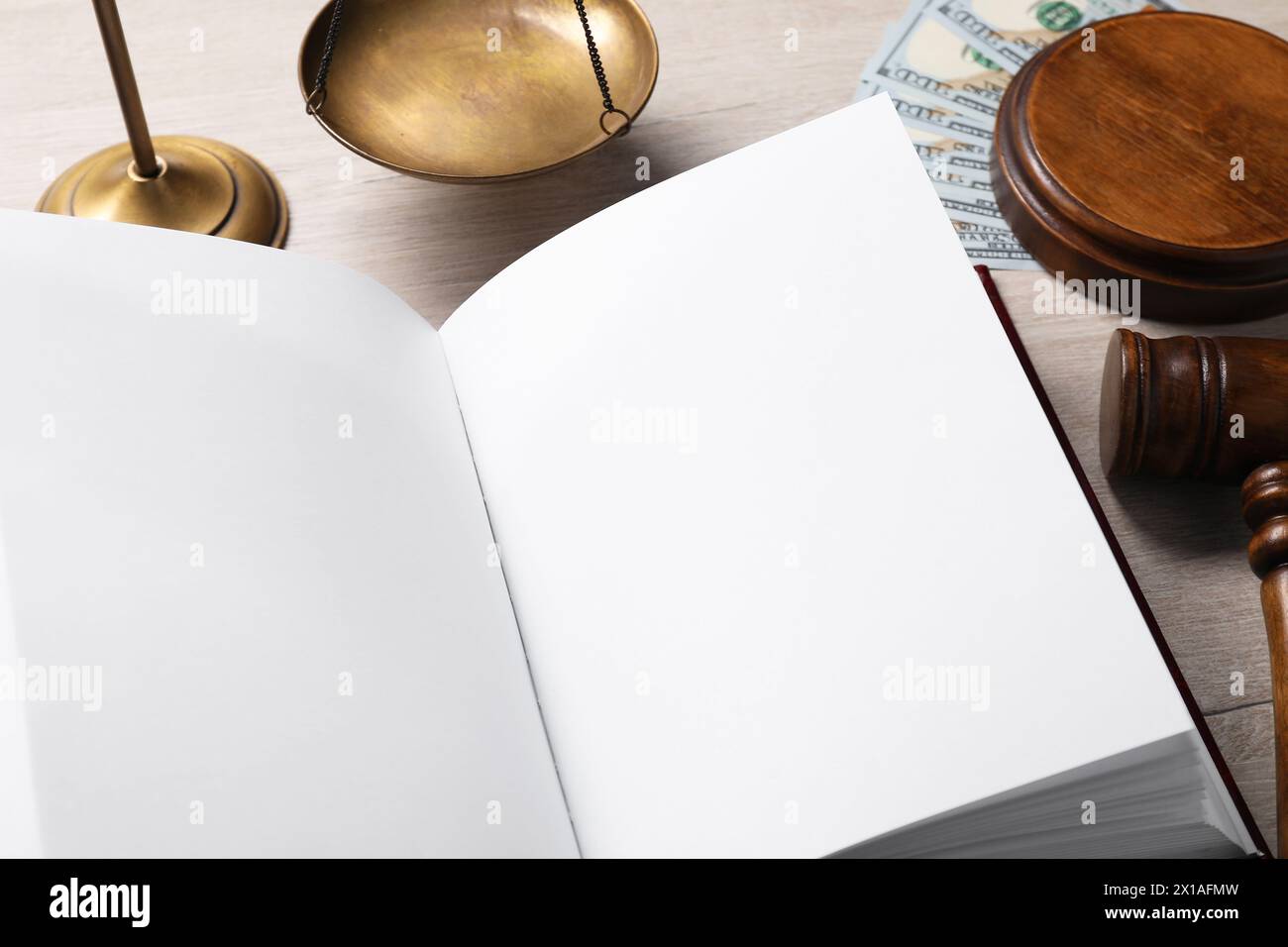 Steuerrecht. Offenes Buch, Hammer, Dollarscheine und Waagen auf Holztisch, Großaufnahme Stockfoto