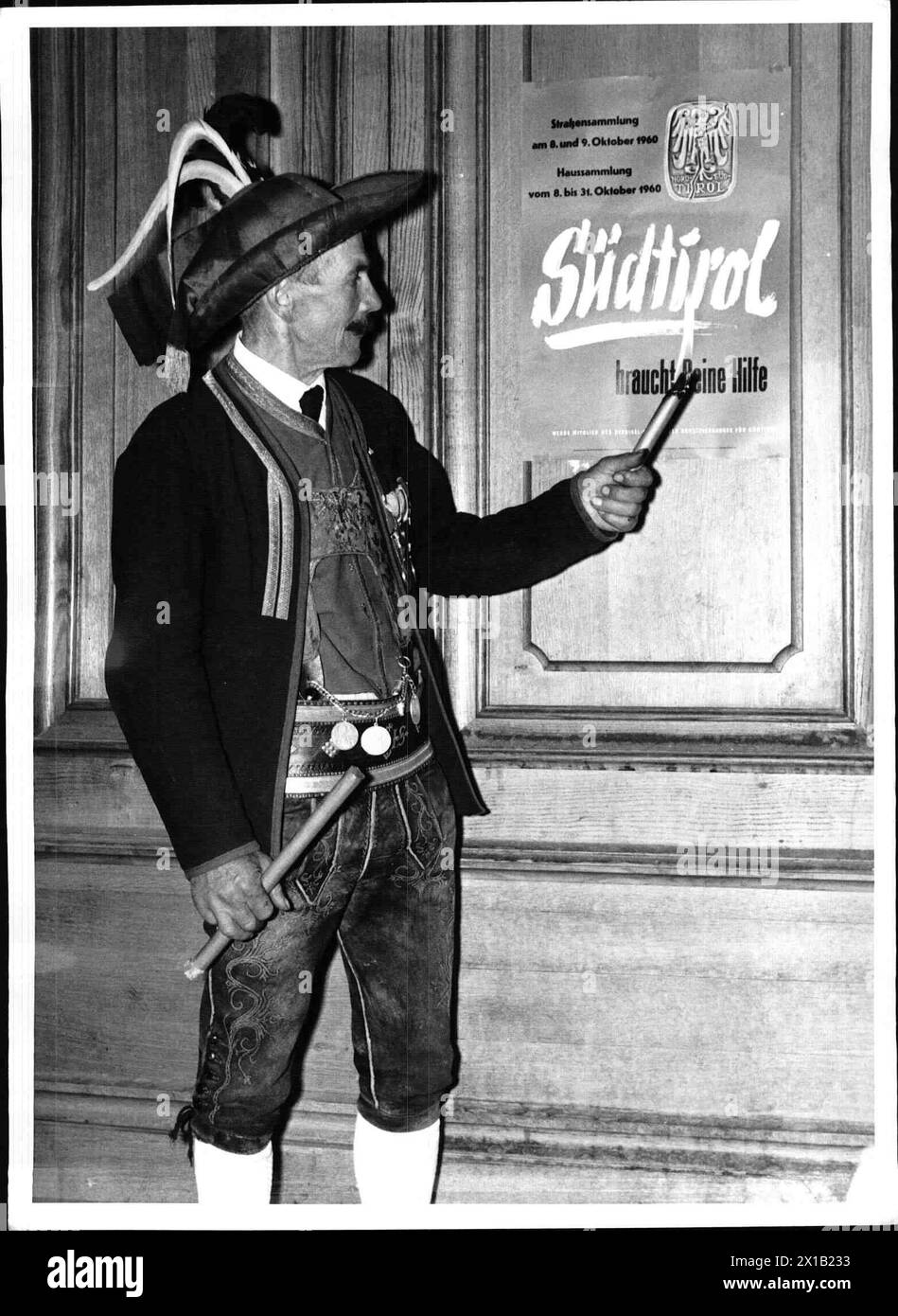 Von einem Tiroler in traditioneller Schützenkostüm, einem Tiroler in traditioneller Schützenkostüm, einer Kerze vor einem Poster, auf dem für eine Sammlung für Südtirol evozieren ist, Text 'Suedtirol braucht deine Hilfe', Anlass ist der 40. Hochzeitstag der Abteilung Südtirol, 1960 - 19600101 PD4617 - Rechteinfo: Rights Managed (RM) Stockfoto