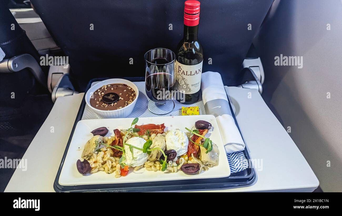 Abendessen in der Business-Klasse an Bord eines Flugzeugs von British Airways, einschließlich Rotwein und Schokoladendessert. Stockfoto