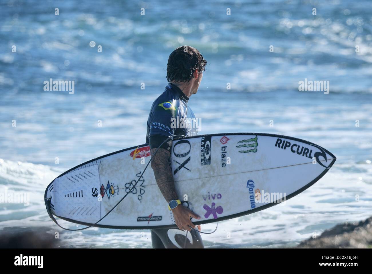Der brasilianische Profi-Surfer Gabriel Medina trug sein Surfbrett, nachdem er 2024 das Wasser beim Margaret River Pro in Western Australia verlassen hatte. Stockfoto