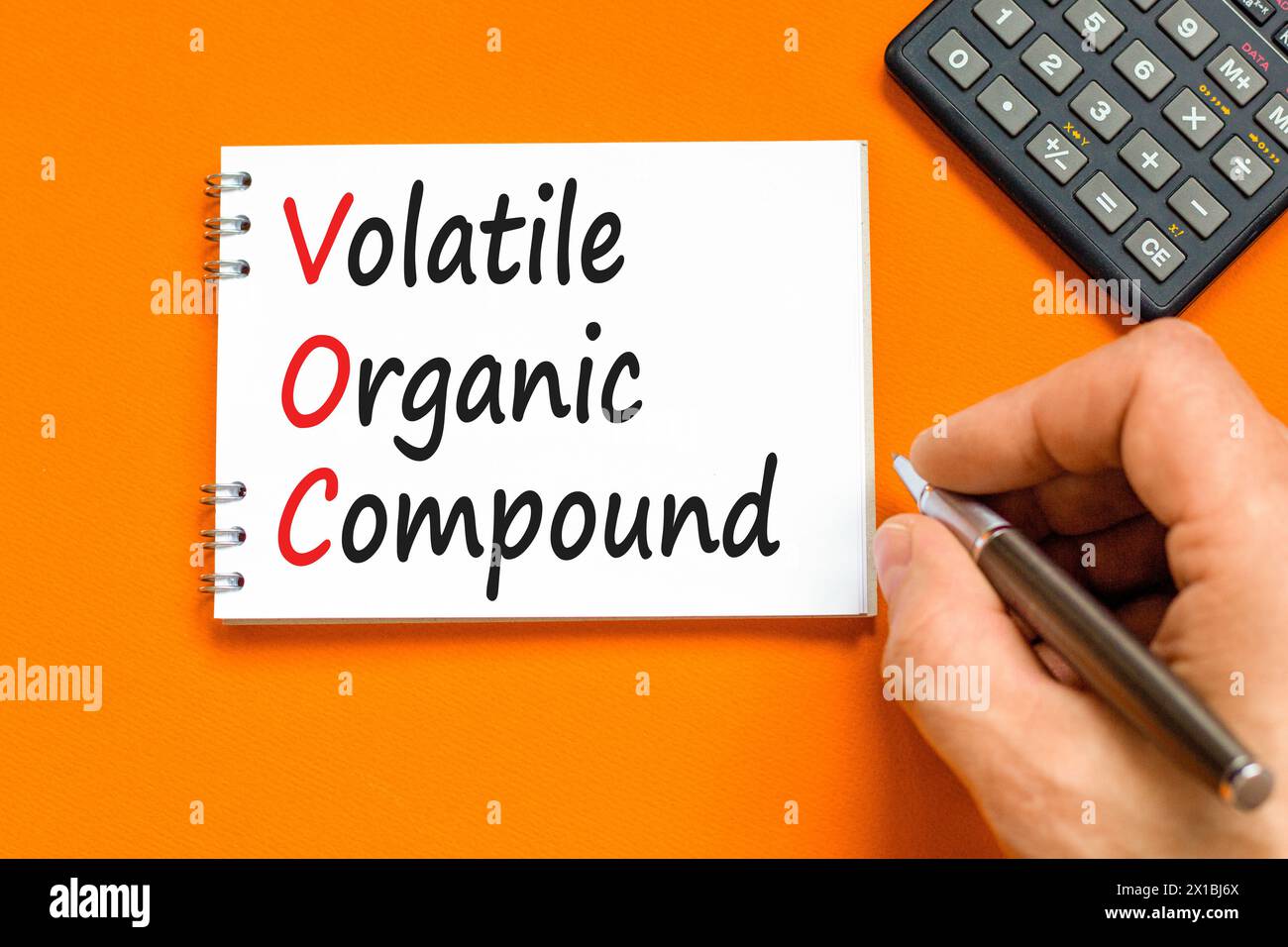 VOC-Symbol für flüchtige organische Verbindungen. Konzeptworte VOC flüchtige organische Verbindung auf schöner weißer Note. Wunderschöner orangefarbener Hintergrund. Business VOC V Stockfoto
