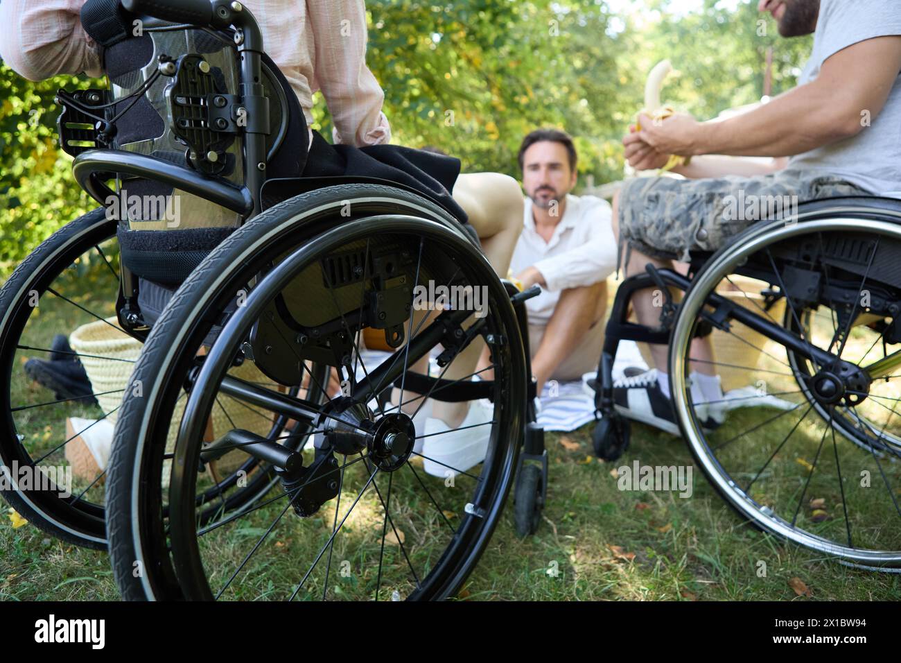Eine friedliche Outdoor-Szene mit zwei Männern, von denen einer im Rollstuhl sitzt, die Inklusivität und Freundschaft in einer natürlichen Umgebung zeigen. Stockfoto