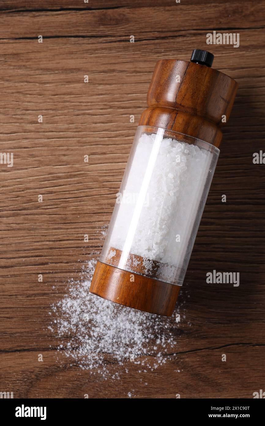 Umgedrehter Shaker mit Salz auf Holztisch, Blick von oben Stockfoto
