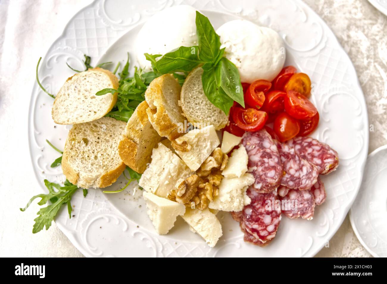 Traditionelle italienische Gerichte auf einem Teller, Salami, Kräuter, Baguette, Tomaten, Stockfoto