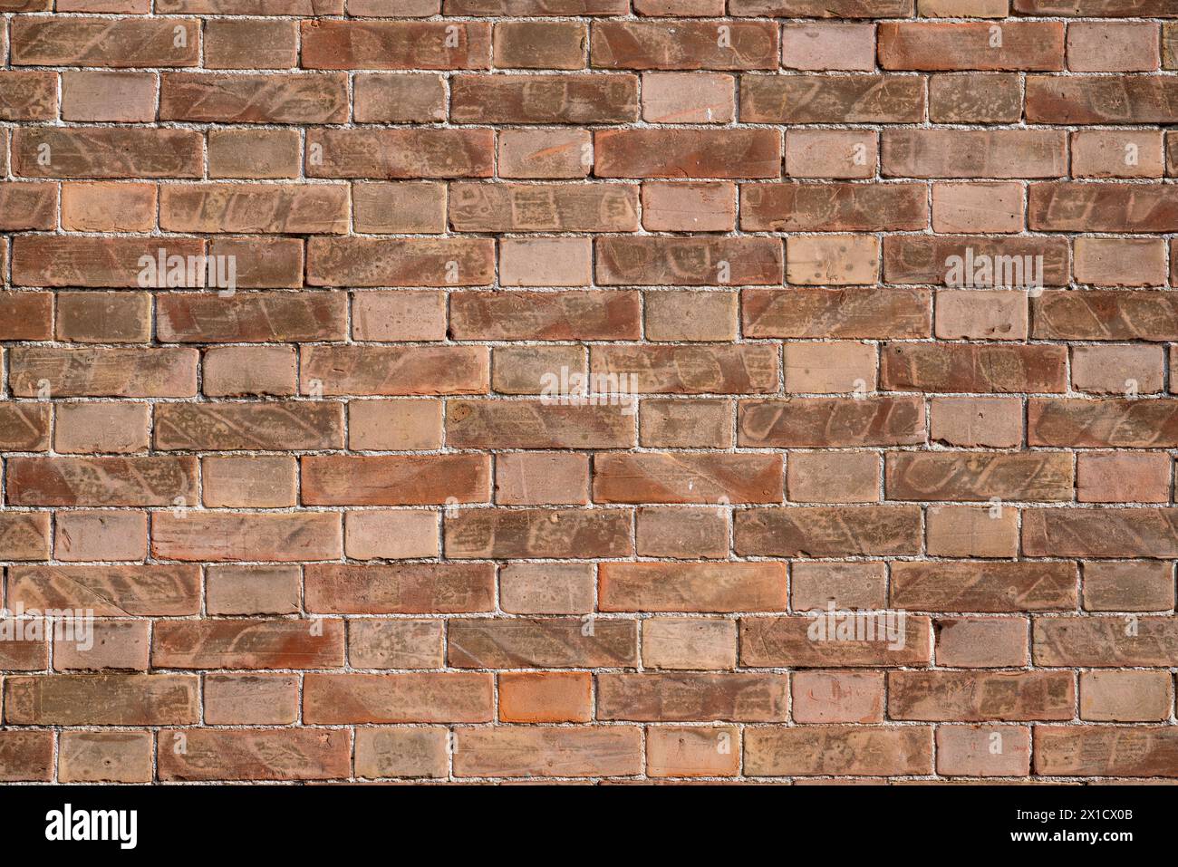 Texturen von Ziegelwänden erzeugen ein Muster, das sich horizontal und vertikal entlang der Wand erstreckt. Die Rottöne, die je nach Zeit und Verschleiß variieren, verleihen Tiefe und Tiefe Stockfoto