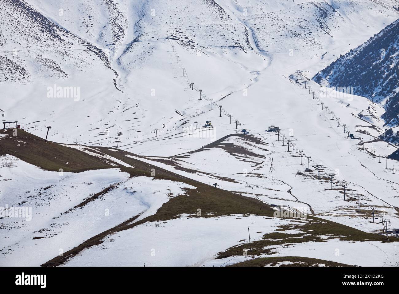 Ende der Saison, leeres Skigebiet. Aufgetaute Flecken auf verschneiten Berghängen. Sessellifte, Blick von oben, aus der Luft. Wintersport, Skifahren, Snowboarder Stockfoto