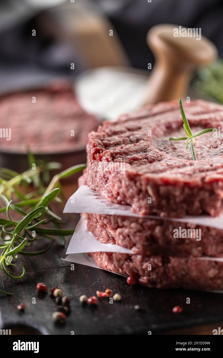 Frisch gemahlene Rindfleischpastete mit Rosmarin-Salz und Pfeffer, in Fleischform auf einem Schneidebrett zubereitet. Stockfoto