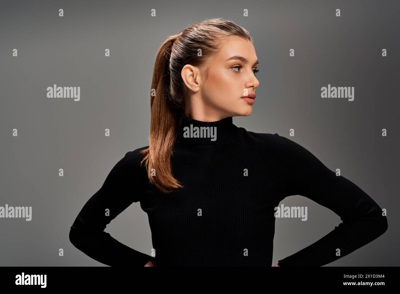 Eine junge, schöne Frau mit langen, welligen Haaren, die mit Händen auf den Hüften in einer selbstbewussten und ausgewogenen Haltung steht. Stockfoto Eine junge, schöne Frau mit langen, welligen Haaren, die mit Händen auf den Hüften in einer selbstbewussten und ausgewogenen Haltung steht. Stockfoto
