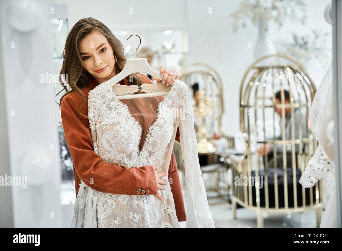 Eine schöne junge Frau hält ein Hochzeitskleid in einem Laden Stockfoto