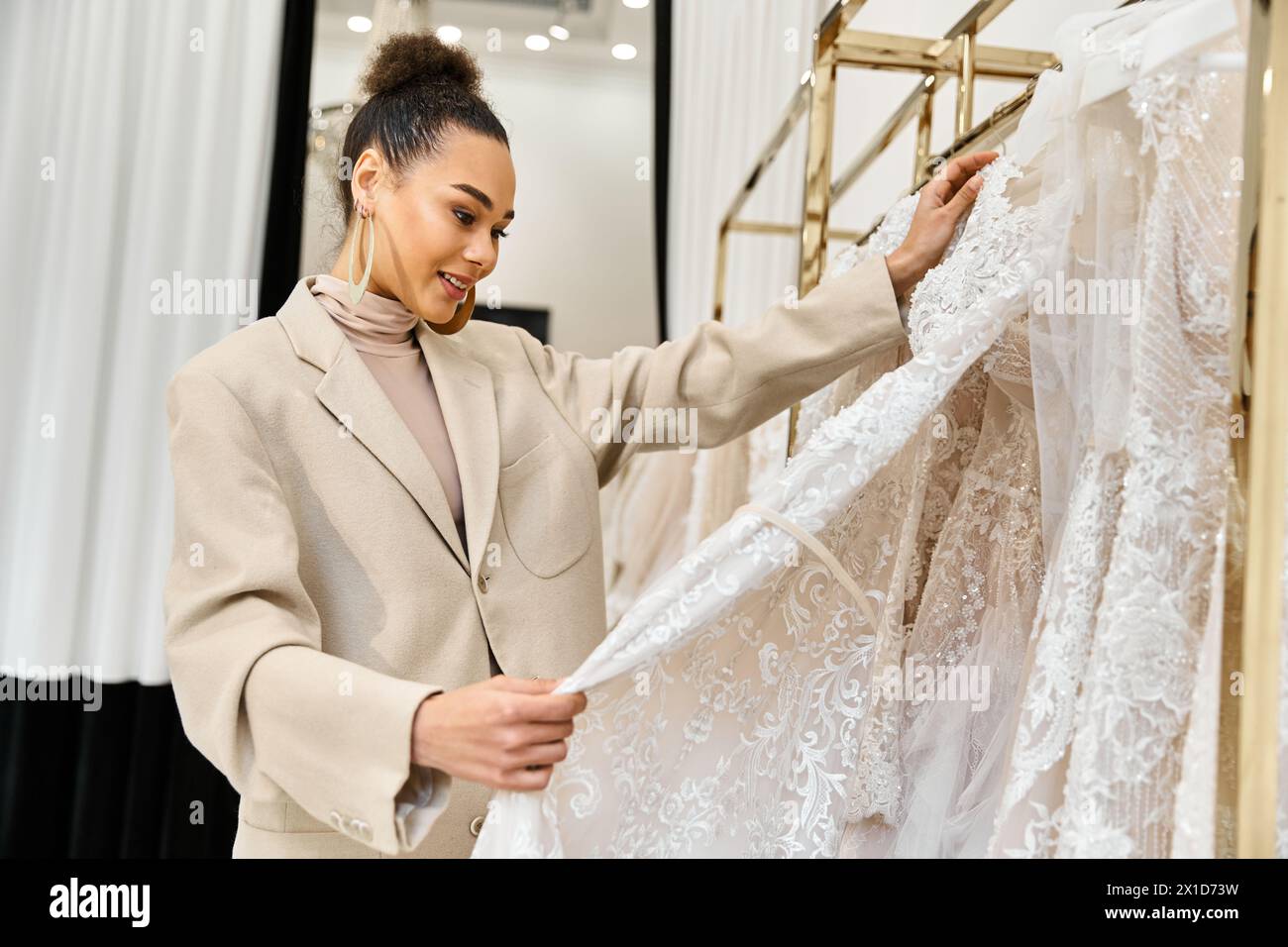 Eine junge, schöne Braut untersucht sorgfältig ein Hochzeitskleid auf einem Ständer Stockfoto