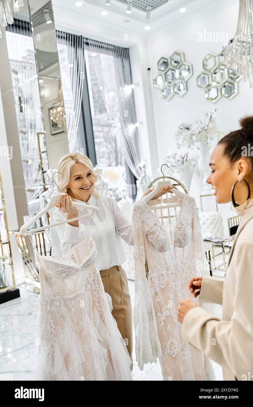Zwei Frauen, eine eine junge, schöne Braut, stöbern in einem Geschäft mit Hilfe eines Verkäufers, umgeben von eleganten Stoffen. Stockfoto