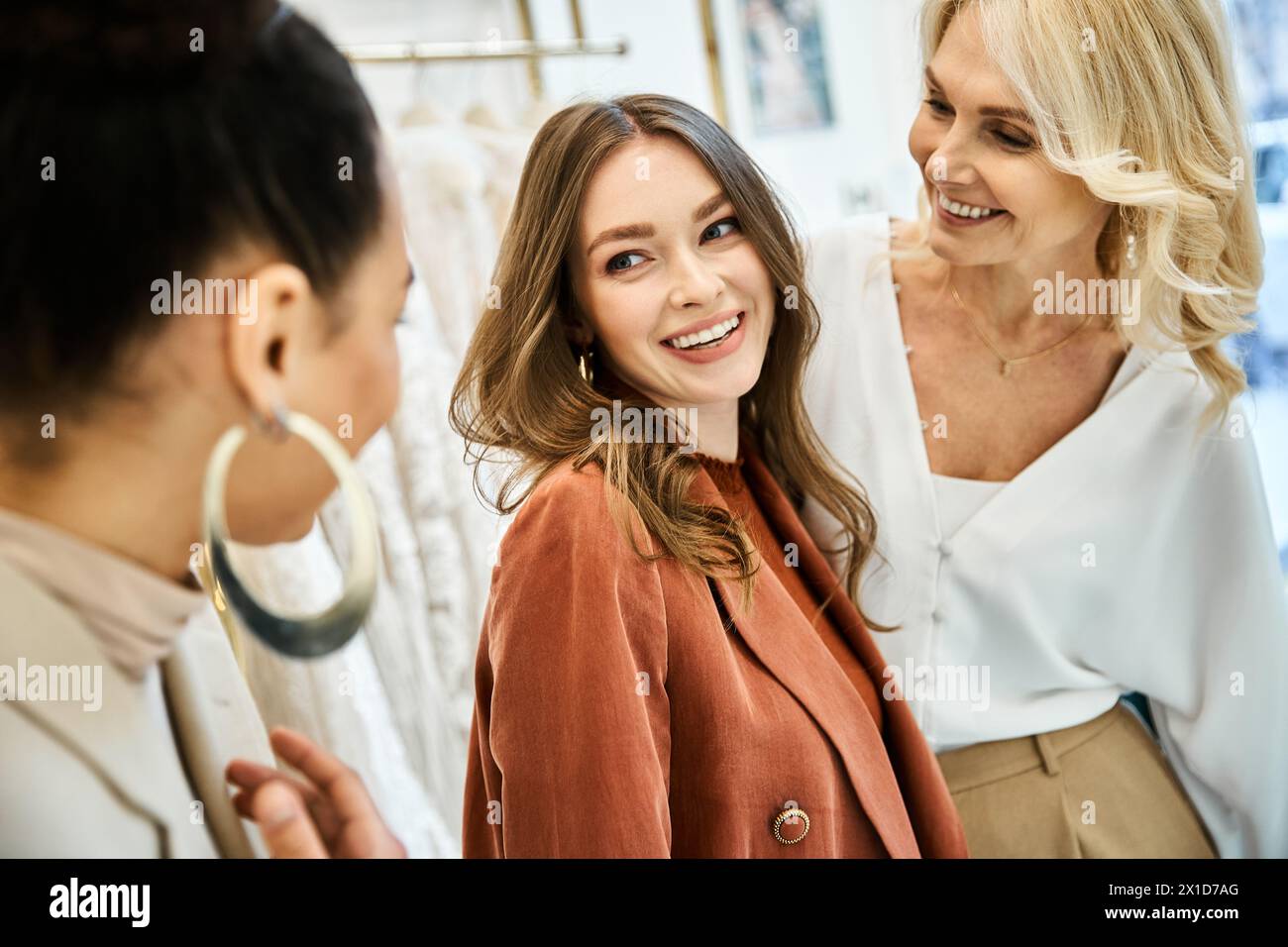 Eine junge Braut, ihre Mutter und ihre beste Freundin durchsuchen Artikel in einem Geschäft, diskutieren Hochzeitspläne und treffen gemeinsam Entscheidungen. Stockfoto