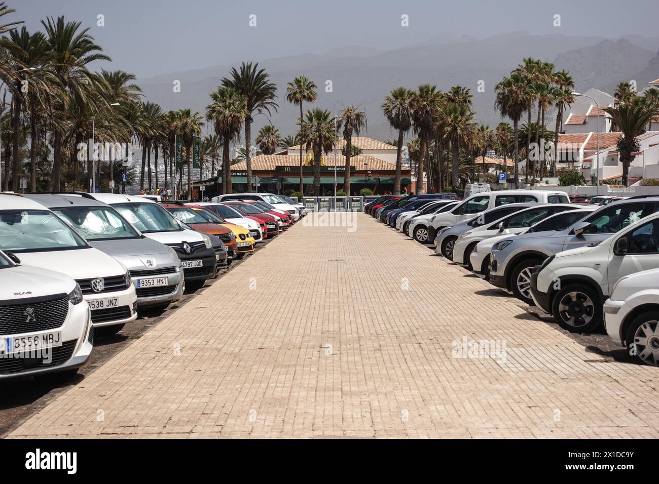 Los Cristianos, Teneriffa, 16. April 2024 - Touristen laufen an Anti-Touristen-Plakaten entlang der Strandfront in Los Cristianos vorbei. Auf dem Poster steht, dass die Kanarischen Inseln eine Grenze haben. Die gelben Schilder werben für den anti-touristischen Protest am Samstag, den 20. April. In Santa Cruz de Teneriffa. Parken ist auch ein großes Problem in der Gegend, da unzählige Besucher Tausende von Plätzen füllen, was für die Bewohner und Besucher gleichermaßen Kopfschmerzen bereitet. Quelle: Stop Press Media/Alamy Live News Stockfoto