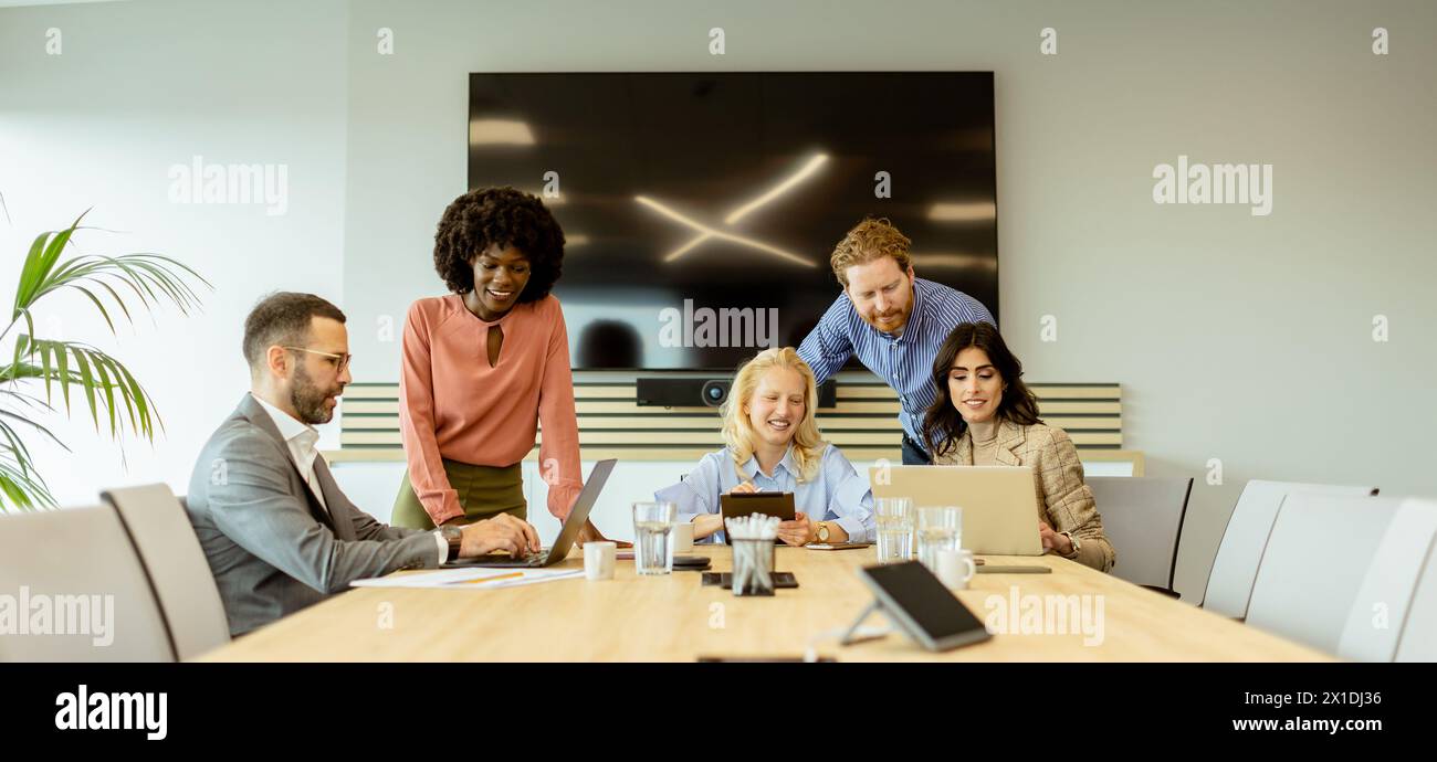 Eine Gruppe von Fachleuten versammelte sich um einen Laptop, um Ideen in einem hellen Büroumfeld auszutauschen. Stockfoto