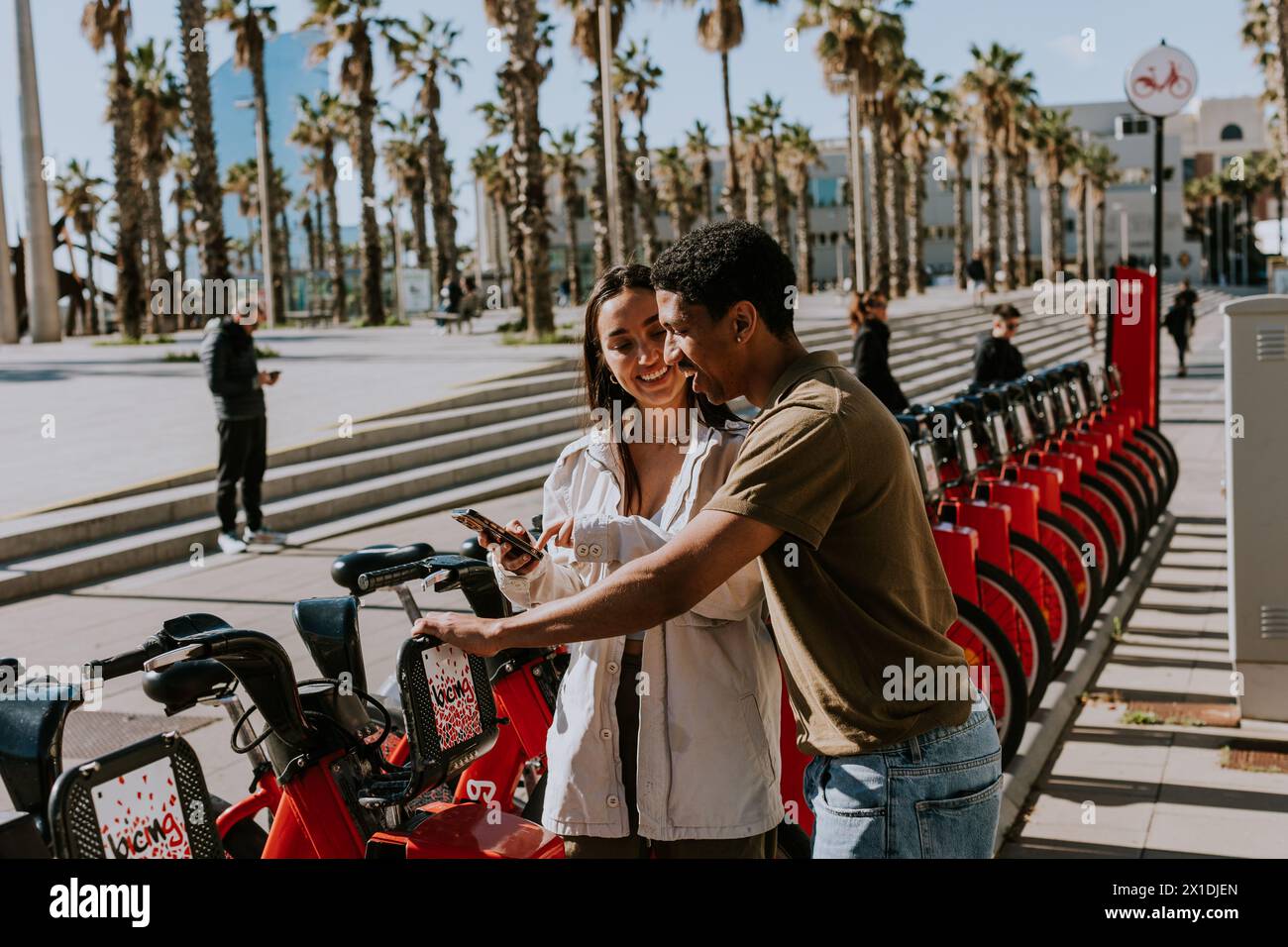 Junge Paare, die einen luftigen Tag mit Fahrrädern von einer Verleihstation in Barcelona verbringen. Stockfoto
