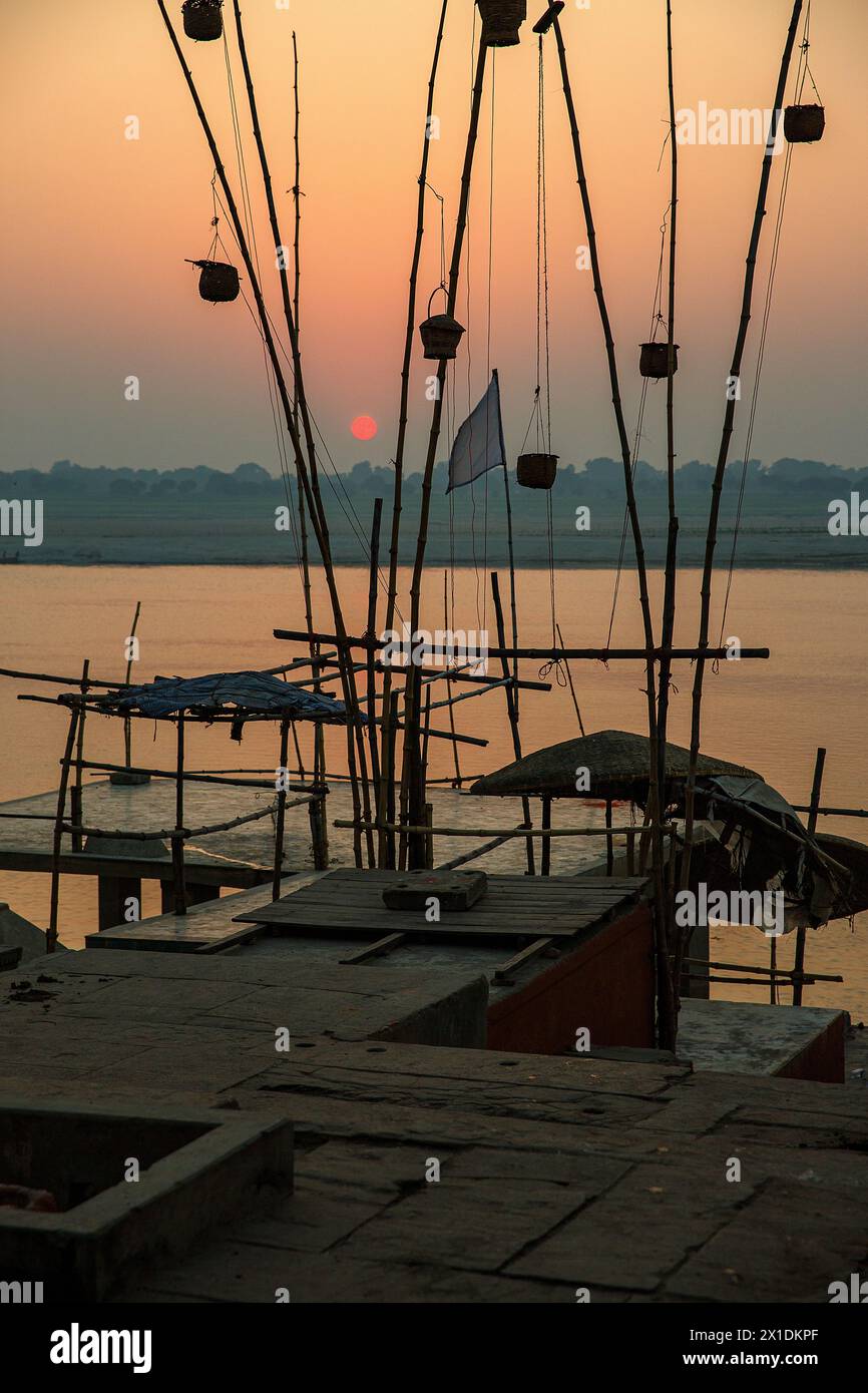 Gewebte Körbe, die bei Sonnenaufgang am Ganges in Varanasi, Indien, an Bambusstangen hängen Stockfoto
