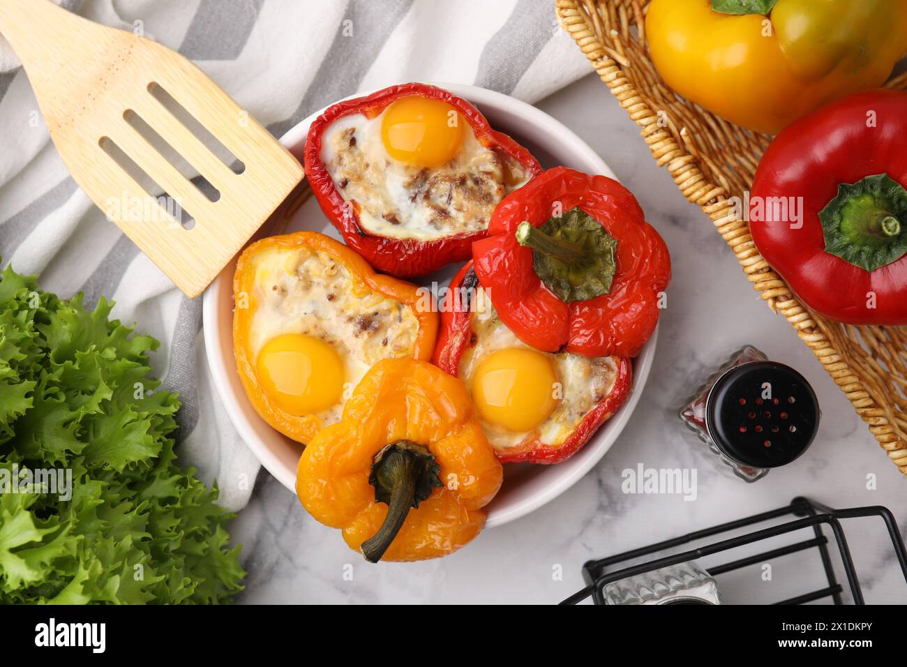 Köstliche gefüllte Paprika in einer Schüssel mit Zutaten und Spachtel auf weißem Marmortisch, flach gelegt Stockfoto