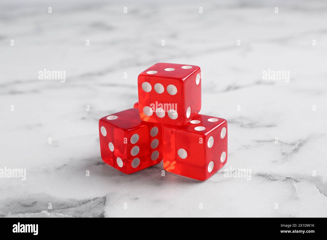 Drei rote Spielwürfel auf weißem Marmortisch, Nahaufnahme Stockfoto