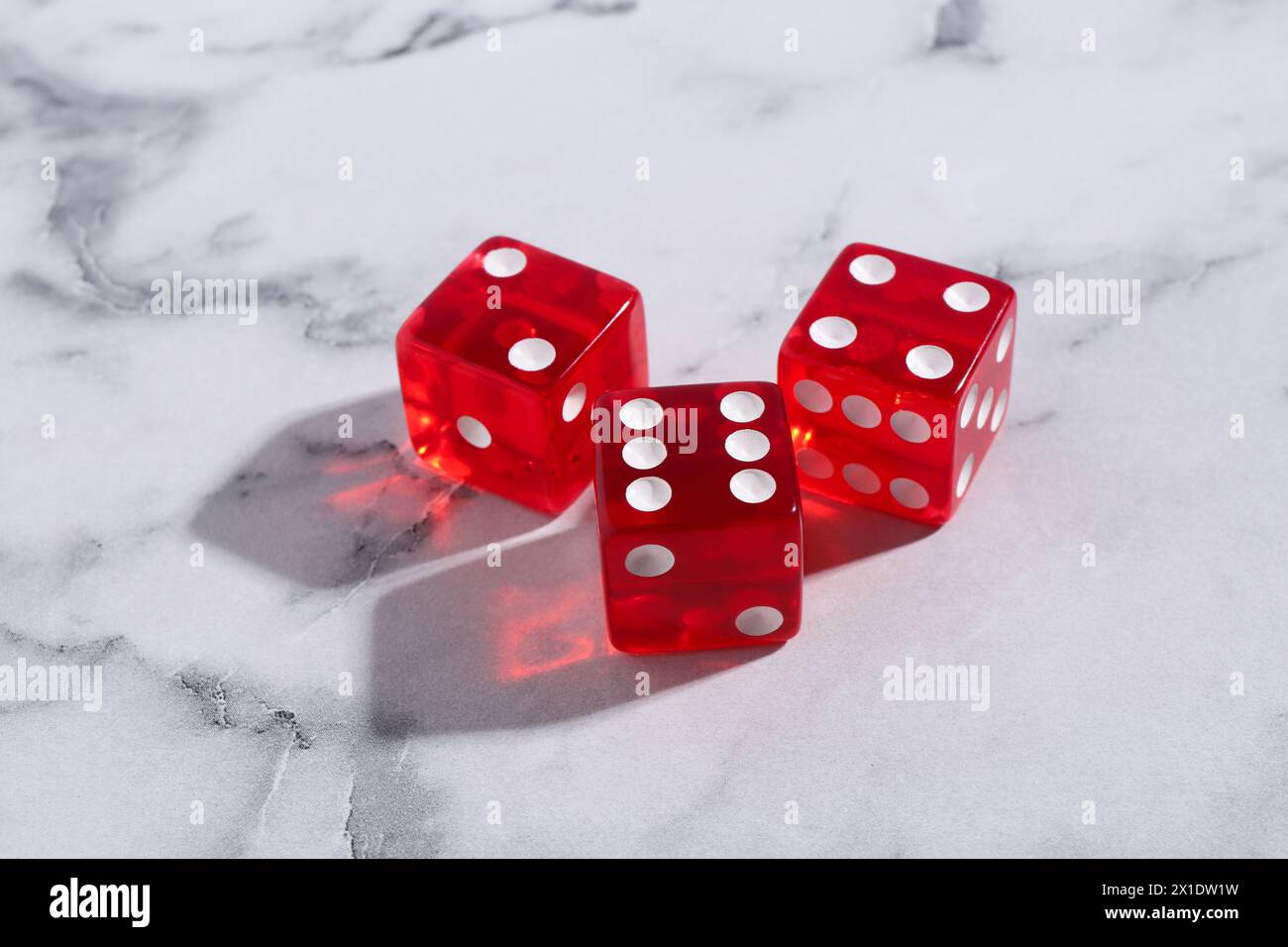 Drei rote Spielwürfel auf weißem Marmortisch Stockfoto