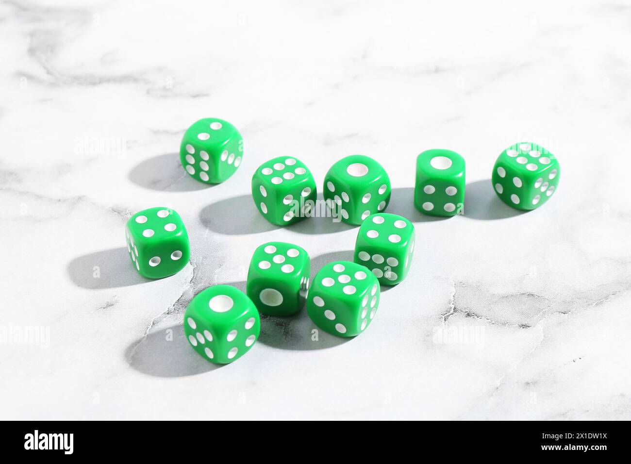 Viele grüne Spielwürfel auf weißem Marmortisch Stockfoto