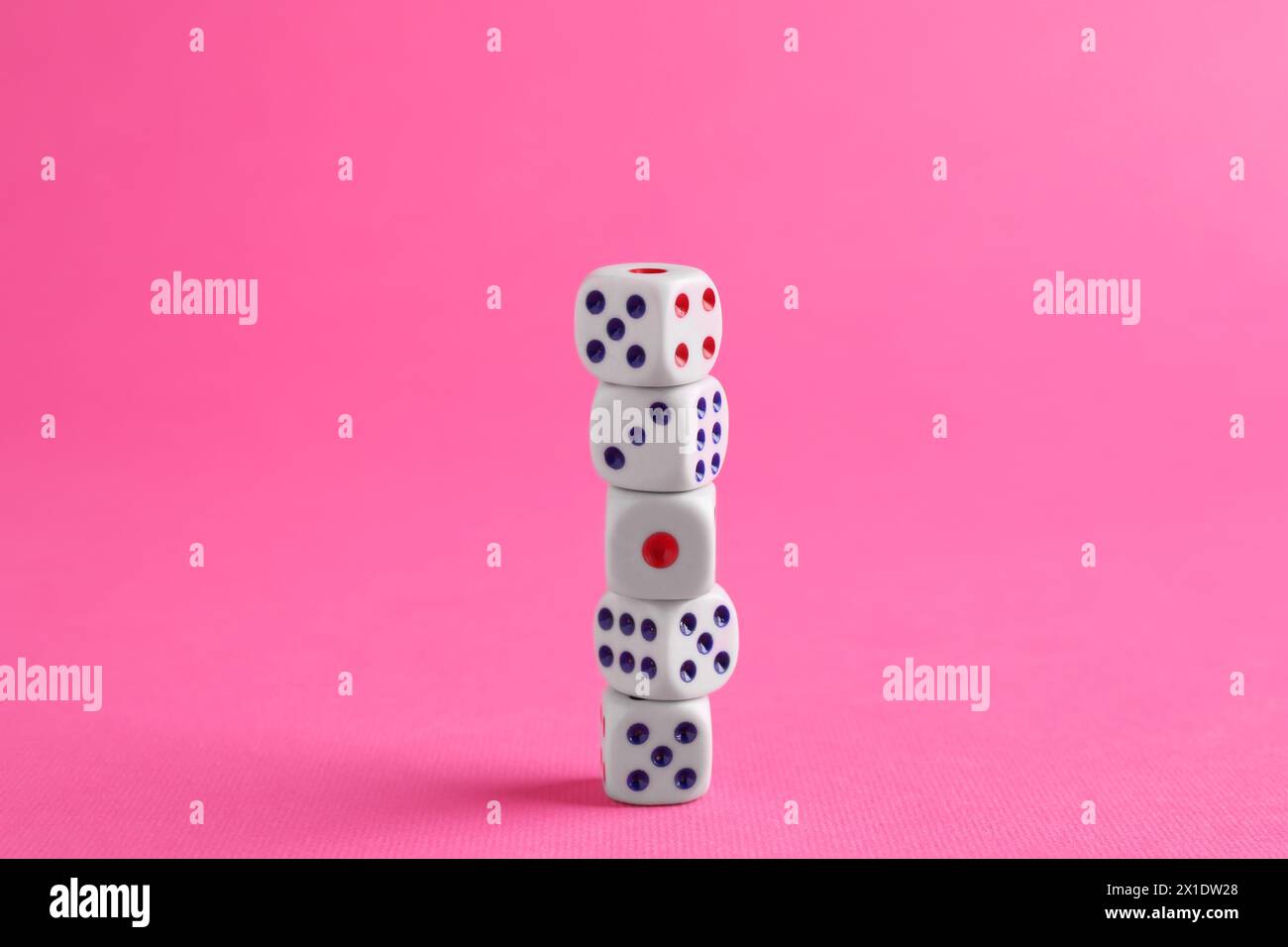 Viele gestapelte Spielwürfel auf rosa Hintergrund Stockfoto