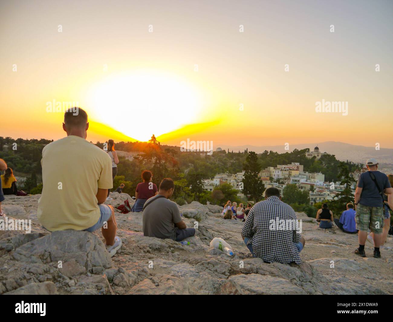 Touristen treffen sich, um den Sonnenuntergang auf dem Areopagus-Hügel in Athen, Griechenland, zu beobachten Stockfoto