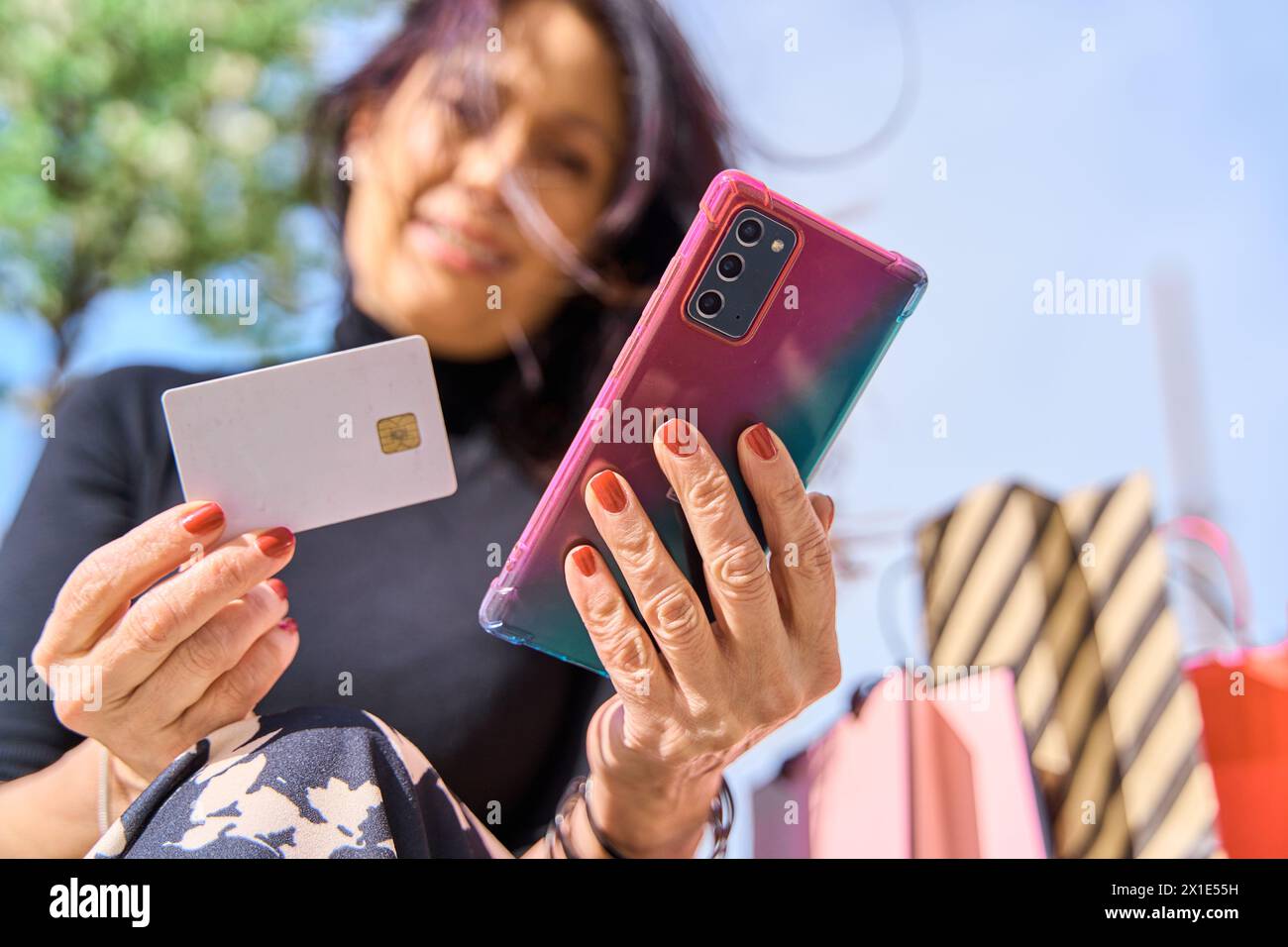 Nahaufnahme einer Frau, die eine Kreditkarte hält und das Smartphone zum Online-Shopping nutzt. Leere Kreditkarte für Kopierraum Stockfoto
