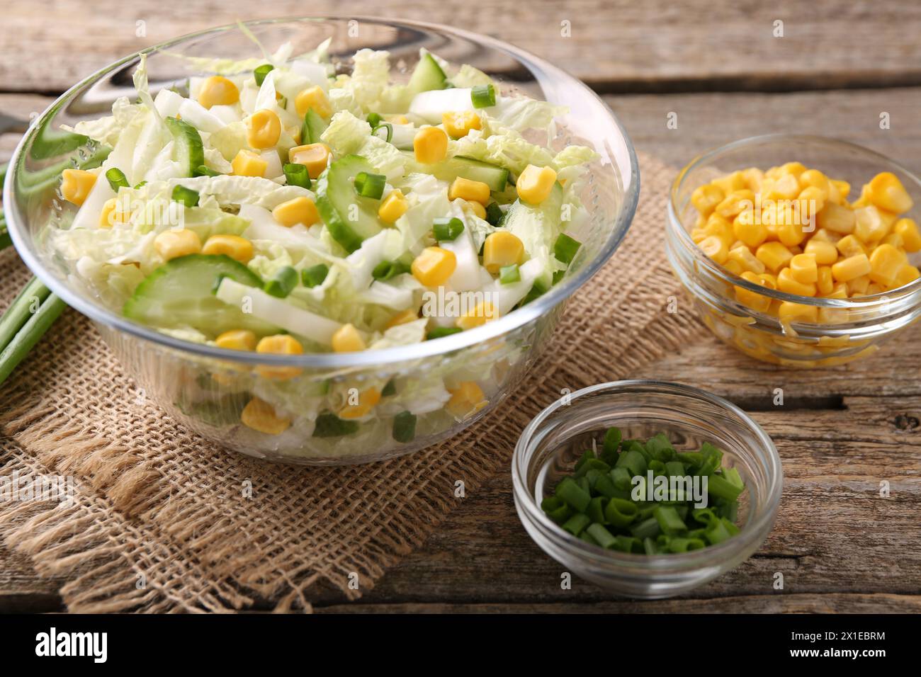 Leckerer Salat mit Chinakohl, Mais und grüner Zwiebel auf Holztisch, Nahaufnahme Stockfoto