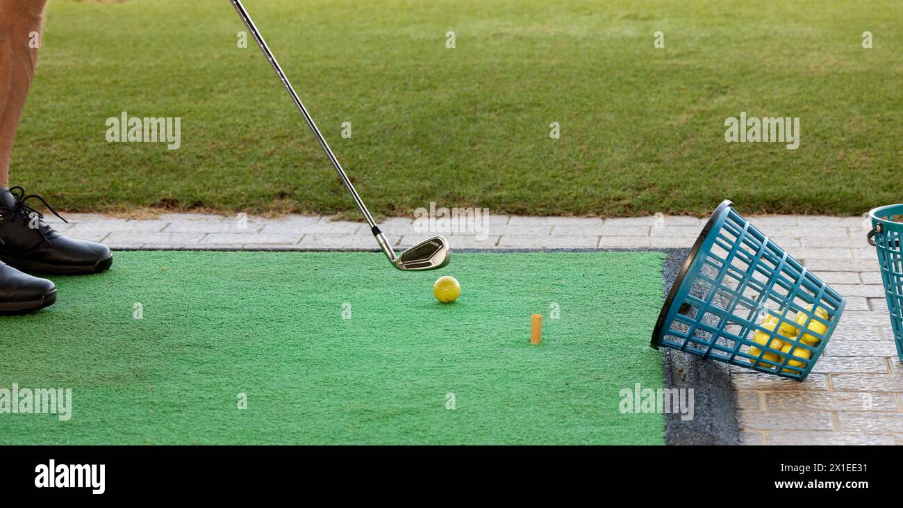Der Golfer übt auf der Driving Range mit einem Golfeisen und mit vielen Bällen, die in den Korb gelegt werden. Stockfoto
