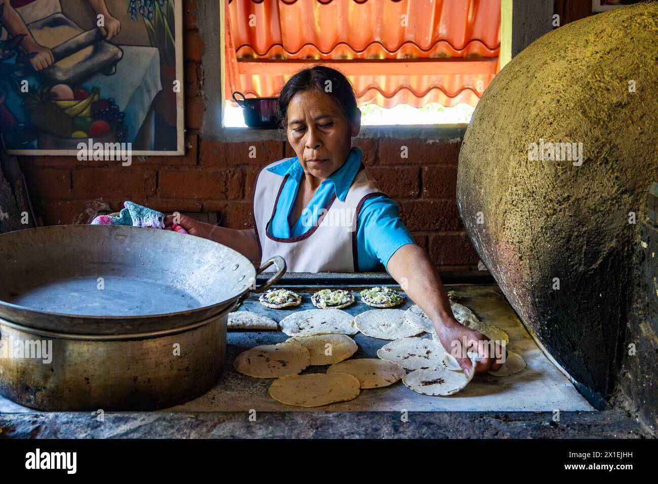 Frau kocht Maistortilla auf traditionellem, flachem Herd. Oaxaca, Mexiko. Stockfoto