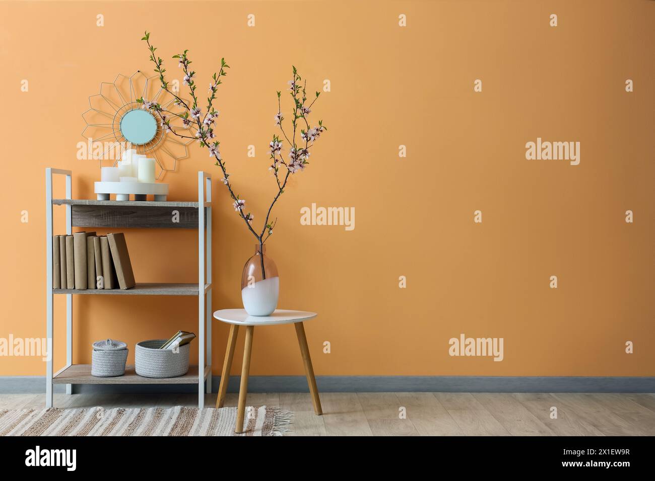 Vase mit blühenden Zweigen auf Couchtisch und Regalfach in der Nähe der beigefarbenen Wand Stockfoto