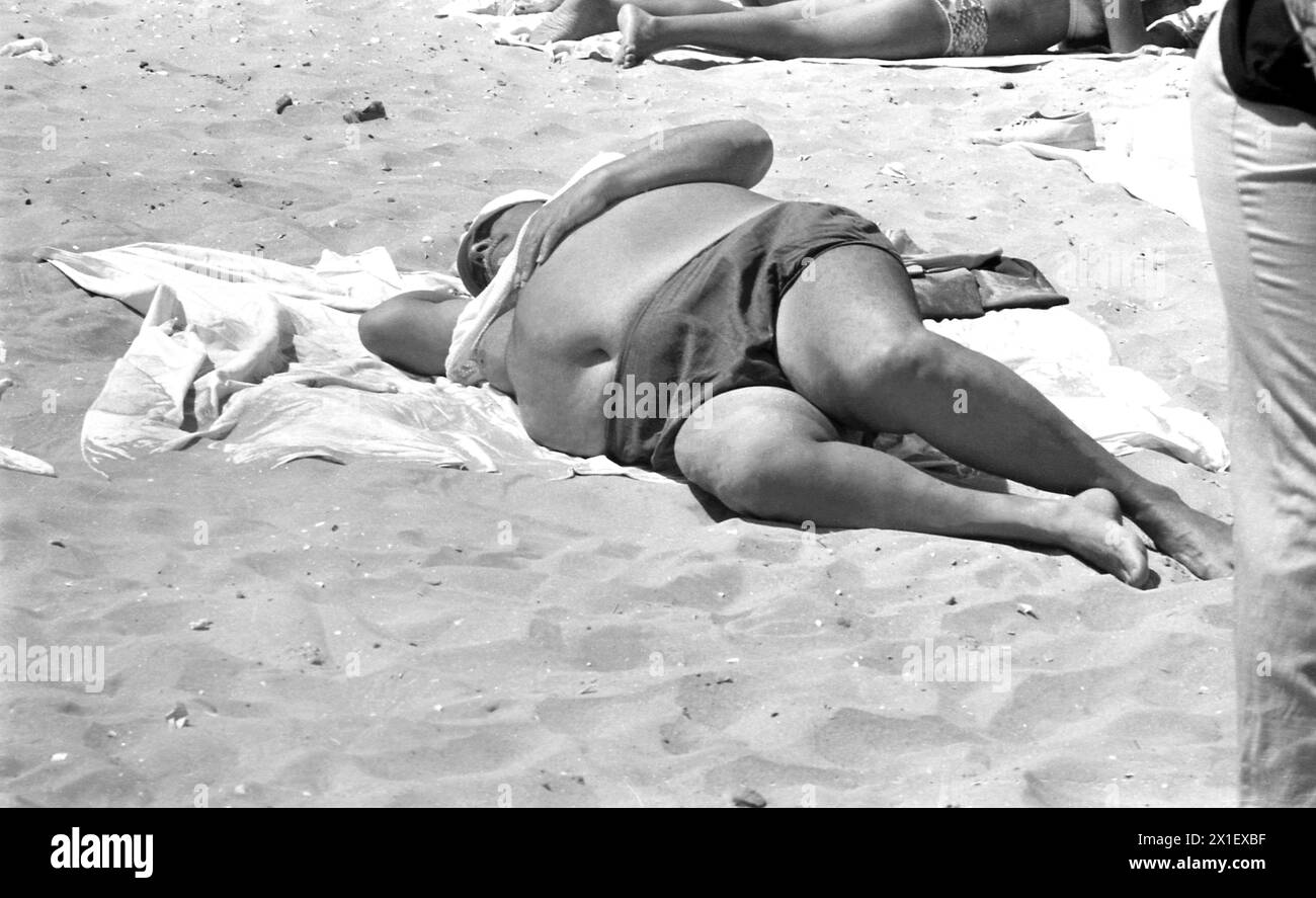 Die Sozialistische Republik Rumänien in den 1970er Jahren Ein übergewichtiger Mann, der am Strand liegt. Stockfoto