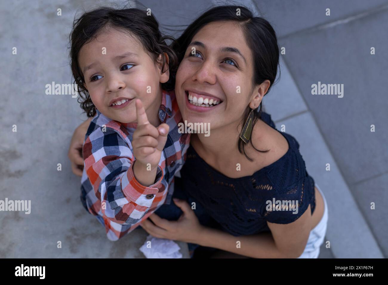 Mom und ihr lateinamerikanischer Sohn sitzen auf einer Bank und zeigen ihre Liebe mit Lächeln und Glück. Muttertagskonzept und Familie Stockfoto