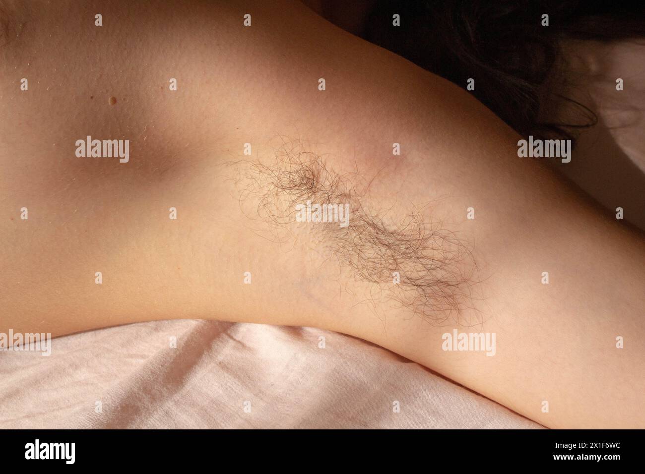 Stellen Sie die Schönheitsstandards heraus und feiern Sie die natürliche Authentizität mit diesem eindrucksvollen Bild einer weiblichen Achselhöhle, die mit Haaren verziert ist Stockfoto