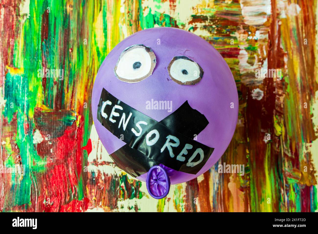 In einer lebhaften Gegenüberstellung von Farbe und Zwang sehen Sie dieses symbolische Bild mit einem Ballon mit verschlossenem Mund, der an einem Hinterkopf aufgehängt ist Stockfoto