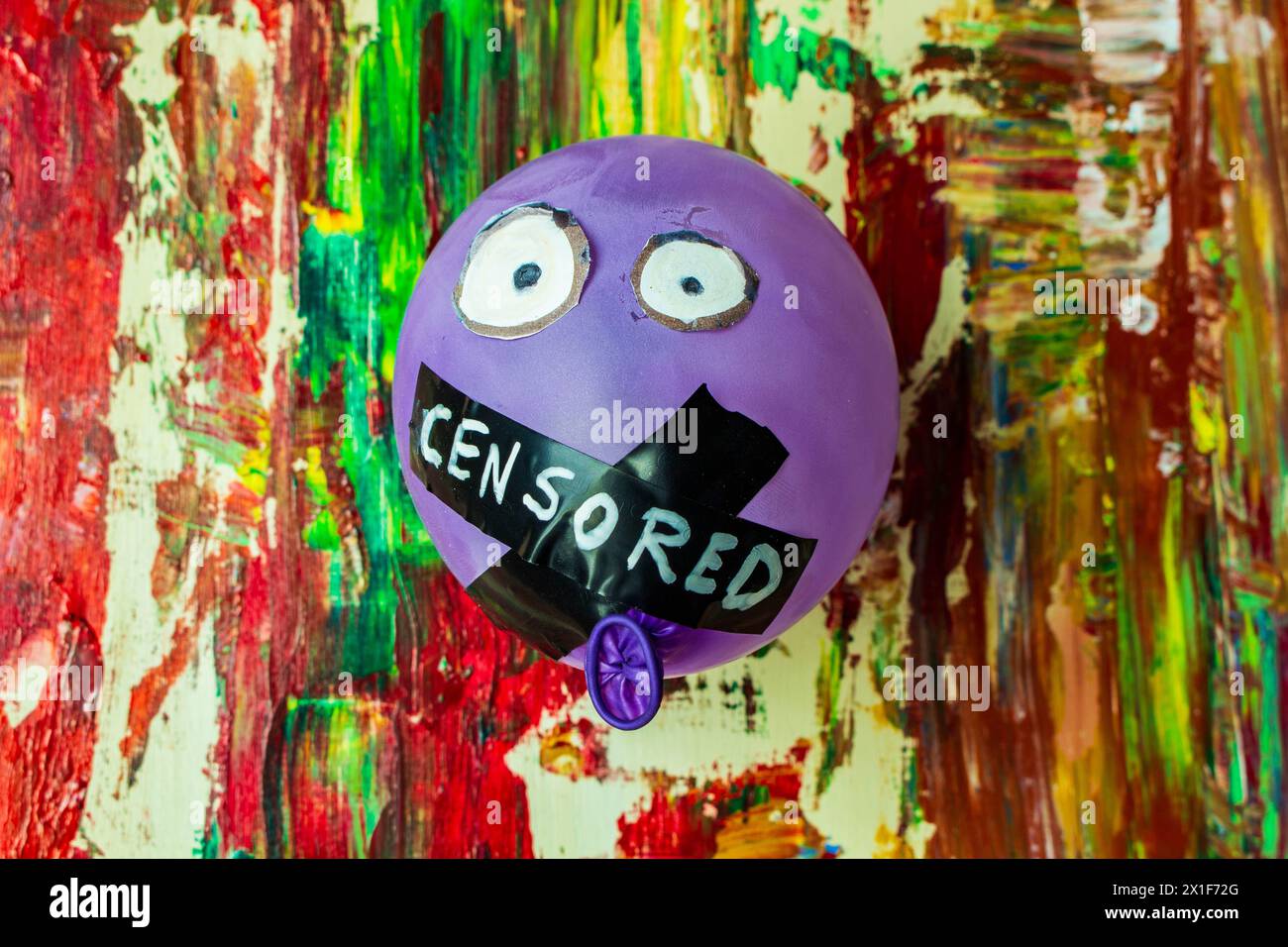 In einer lebhaften Gegenüberstellung von Farbe und Zwang sehen Sie dieses symbolische Bild mit einem Ballon mit verschlossenem Mund, der an einem Hinterkopf aufgehängt ist Stockfoto
