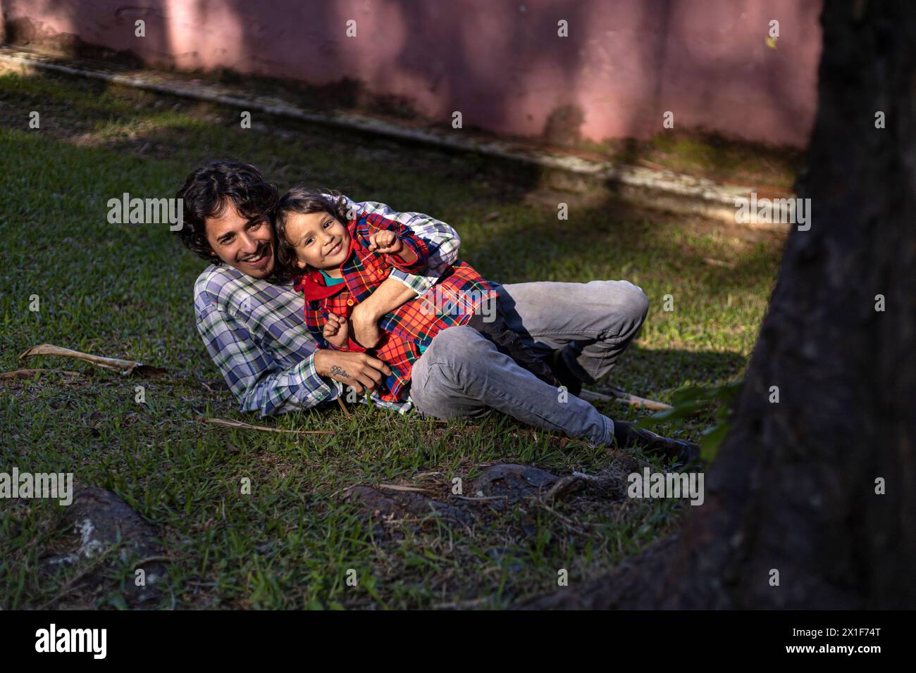 Lateinamerikanischer Vater trägt seinen dreijährigen Sohn in den Armen im Park. Stockfoto