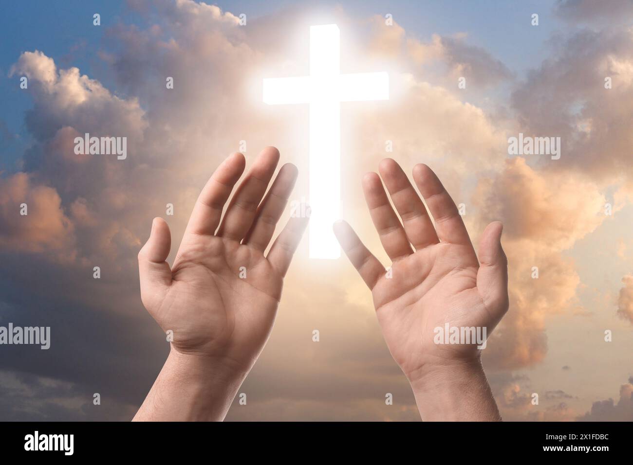 Religion. Christlicher Mann betet gegen den Himmel mit glühendem Kreuz, Nahaufnahme Stockfoto