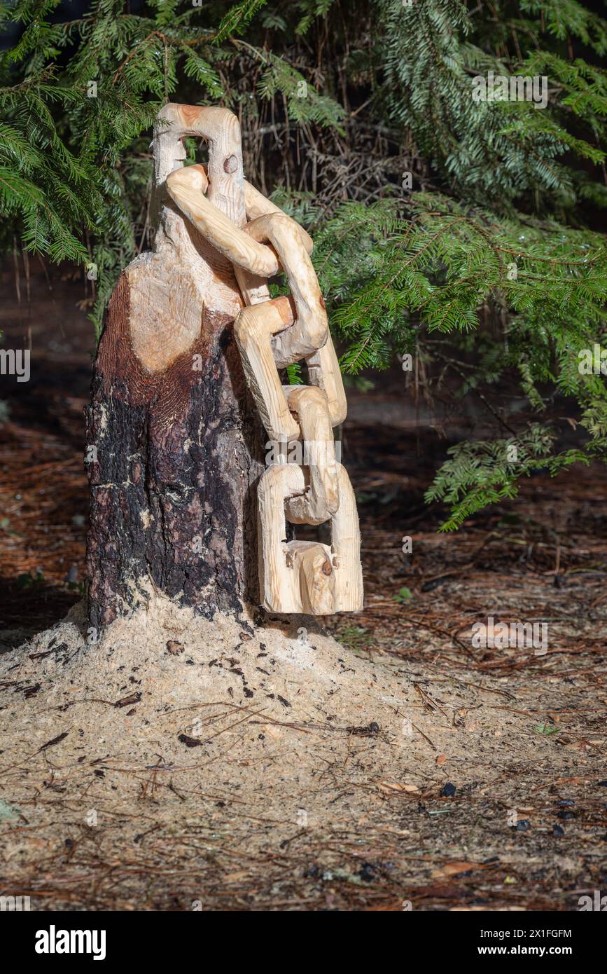 Aus einem Baumstumpf wird eine Kette mit Sägemehl auf dem Boden geschnitzt. Die Szene ist friedlich und ruhig. Stockfoto