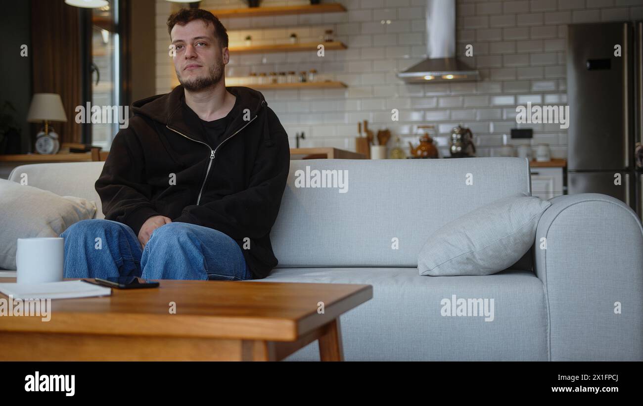 Der Mann legt sich auf das Sofa und macht ein Nickerchen mit legeren Klamotten. Erholung und Entspannung nach einem anstrengenden Arbeitstag und Pause im Wohnzimmer zu Hause. Stockfoto