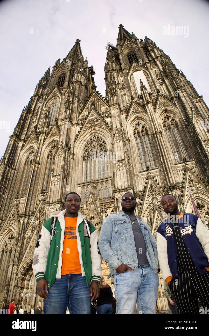 Köln, Deutschland, 12. April 2024. Drei afrikanische Männer posieren für ein Gruppenfoto vor dem Kölner Dom. Stockfoto