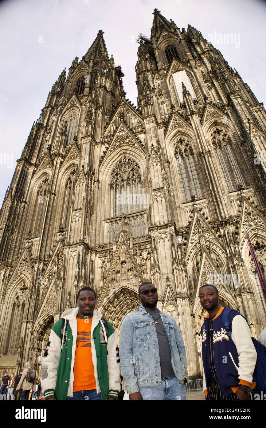 Köln, Deutschland, 12. April 2024. Drei afrikanische Männer posieren für ein Gruppenfoto vor dem Kölner Dom. Stockfoto