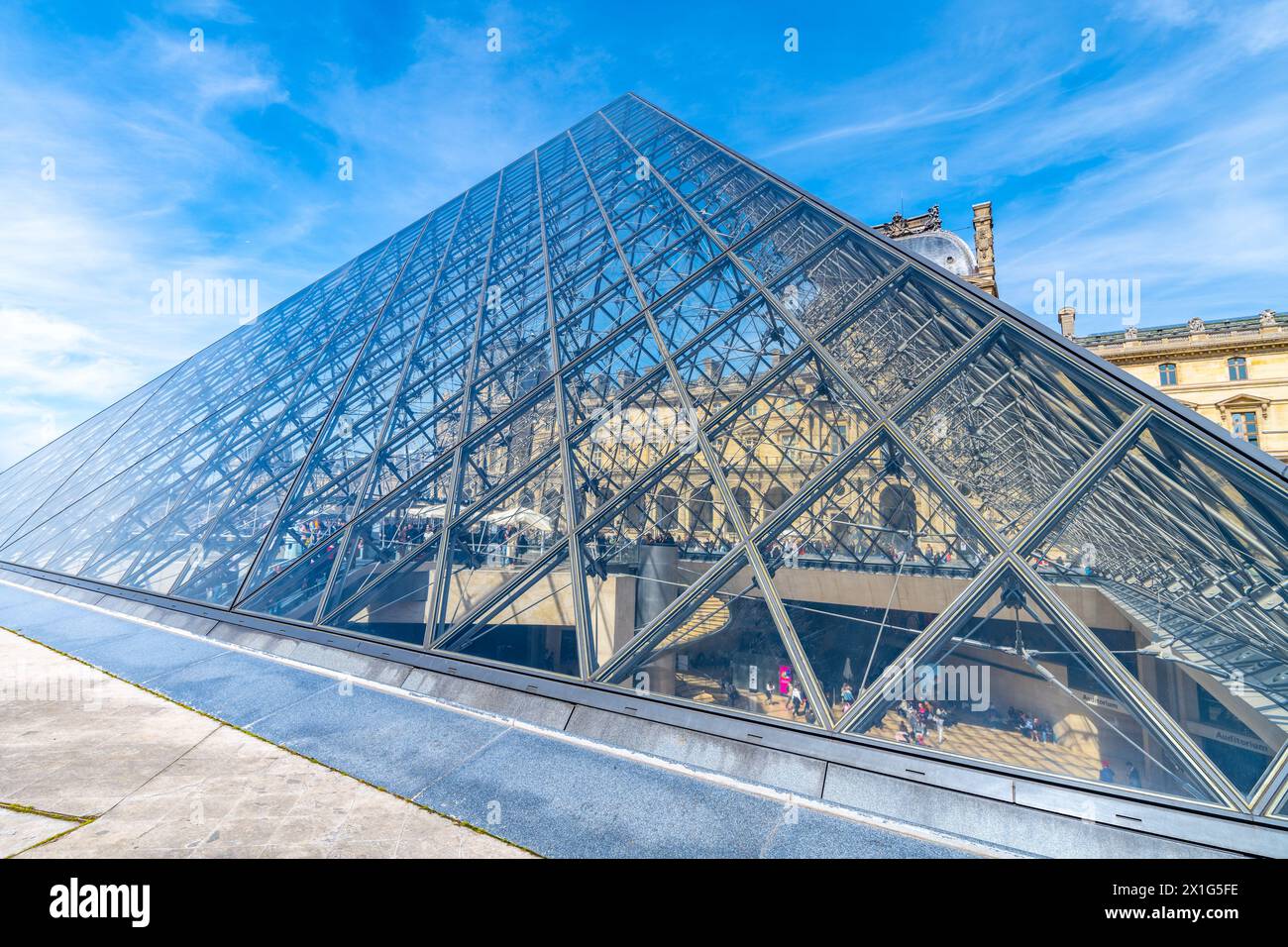 Die ikonische Glaspyramide im Louvre sonnt sich unter einem klaren blauen Himmel. Paris, Frankreich Stockfoto