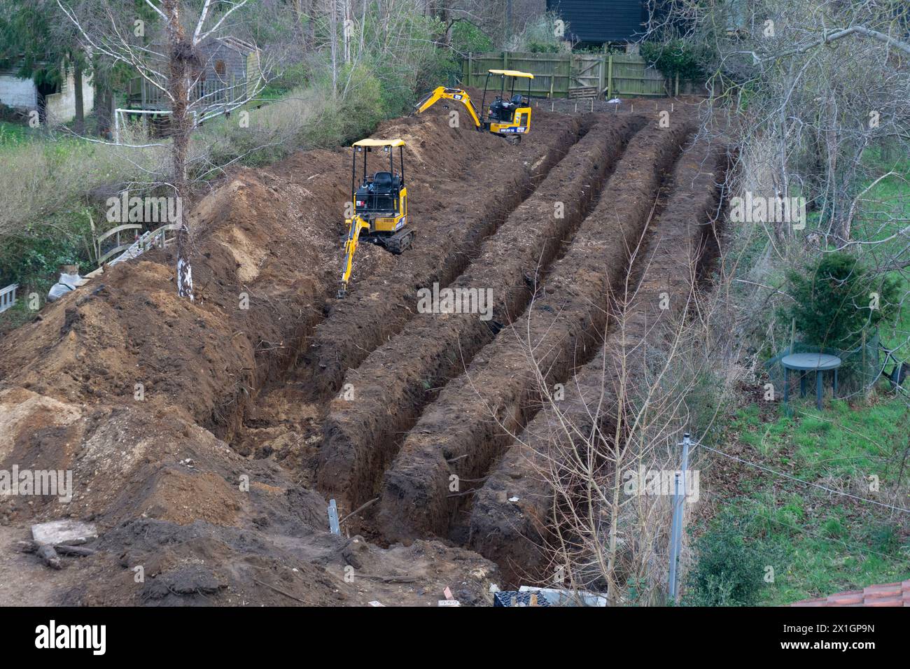 Hinterhof des Wohngartens mit Minibagger für Heizungsanlage der Erdwärmepumpe Stockfoto