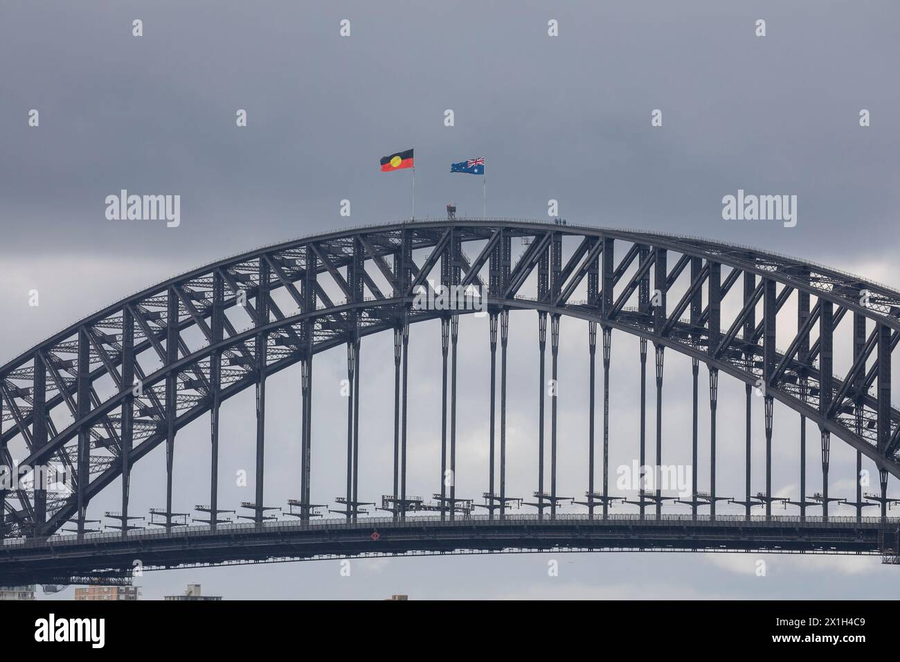 Die berühmte Sydney Harbour Bridge, die Flaggen der Aborigines und australiens, die auf dem Gipfel fliegen, die Menschen, die den Bogen vom Brückenkletterausflug hinunterlaufen, Sydney, NSW Stockfoto