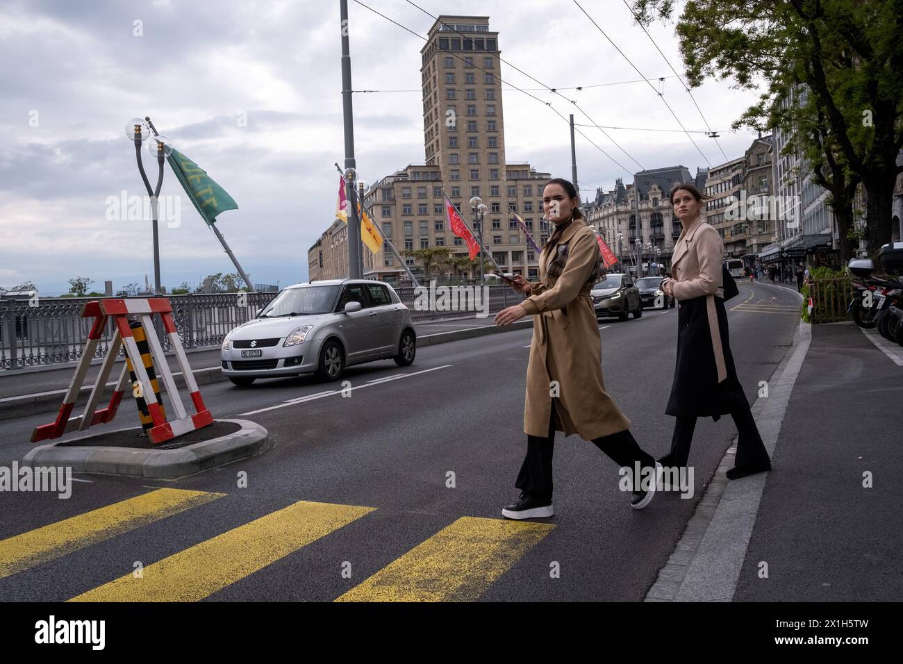 Zwei junge Frauen in luxuriöser Kleidung überquerten am 19. Mai 2023 in Lausanne die Straße mit dem Bel-Air-Turm im Hintergrund. Lausanne ist ein Stockfoto