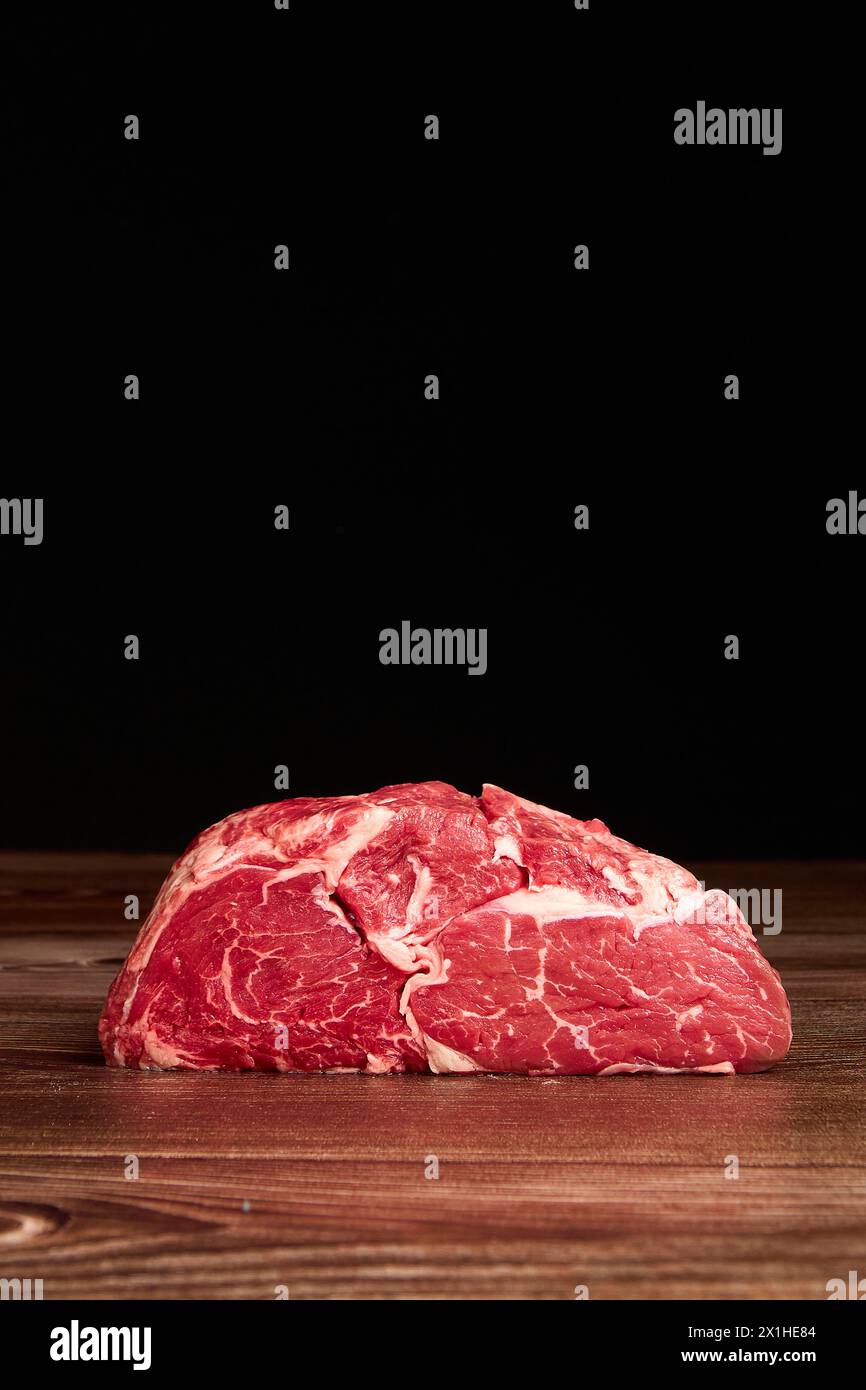 Fleischvorschnitt auf einem Holztisch vor dunklem schwarzem Hintergrund Stockfoto